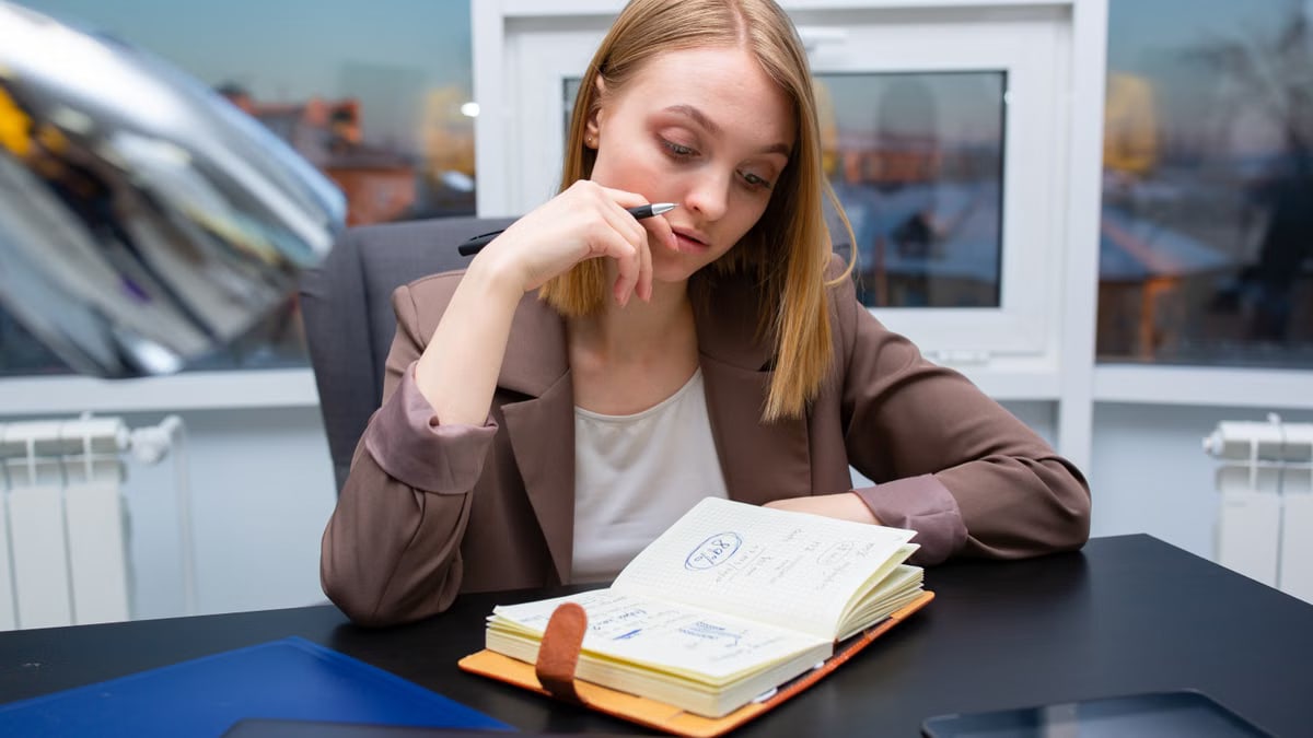 Thoughtful businesswoman planning her schedule at a modern office desk.